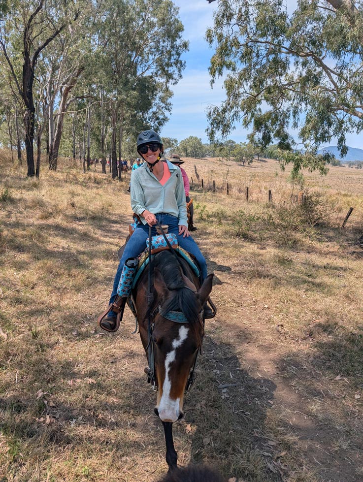 girl riding a horse in bush setting
