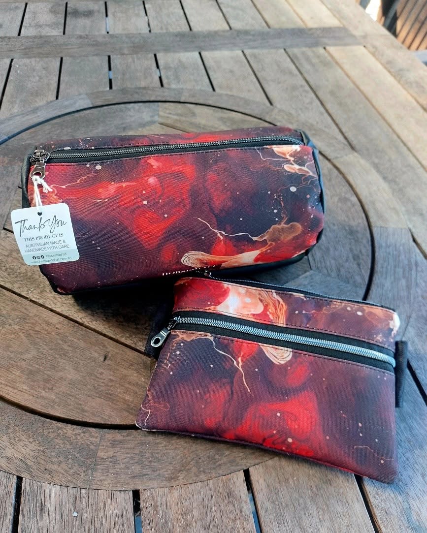 Two pouches with a red and black abstract design on a wooden surface